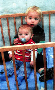 Aaron with baby brother Samuel in the cot.